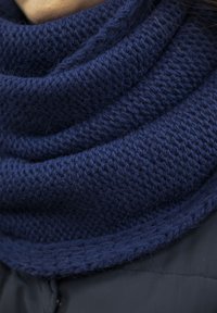 Sötétkék kötött cowl sál texturált, bordás mintával. Puha fonal sima felülettel, felhajtott széllel a további részletekért.