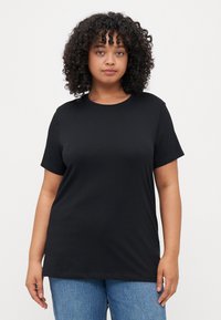 Black cotton t-shirt with a crew neckline and short sleeves. Features a relaxed fit and smooth texture. Paired with blue jeans.