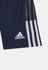 Pantalones cortos deportivos en color navy con tres franjas verticales blancas y detalles de malla en los laterales. El logo de "Adidas" se muestra de manera prominente en blanco.