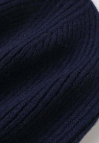 Marineblaue gestrickte Mütze mit Rippstruktur, aus weicher Wolle gefertigt, mit subtilen horizontalen Linien und einer abgerundeten Oberseite.