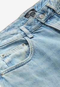 Světle modré džíny z denimu s klasickým pětikapsovým designem, viditelným švem, kovovým kováním a značkovou nálepkou na pásku.