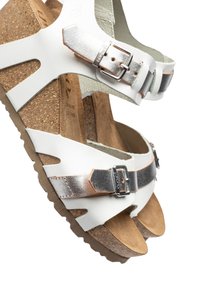 Sandales blanches avec semelle en liège, accents métalliques argentés et boucles ajustables. Présente un design à bout ouvert et une semelle texturée pour une meilleure adhérence.