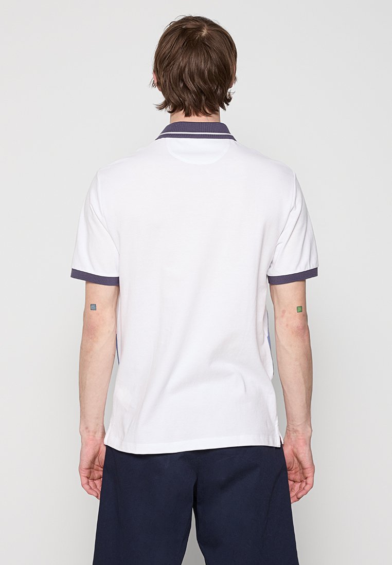 Polo en coton blanc avec col et poignets de manches navy. Coupe régulière avec manches courtes et un dos uni. Texture douce.