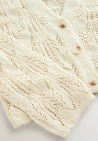 Cardigan in maglina di colore avorio con un motivo a onde testurizzato, cinque bottoni e polsini a costine. Tessuto morbido e leggero con un design in pizzo.