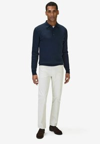 Mörkblå ribbad långärmad polo skjorta matchad med ljusbeiga byxor och mörkbruna skor. Enkelt mönster med klassisk polokrage.