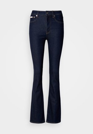 Dunkelblaue Schlagjeans aus Denim, mit hoher Taille, Fronttaschen und Kontrastnähten. Glatte Textur mit minimaler Detailierung.
