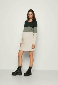 Vestido de maternidade de malha com mangas longas, com blocos de cor horizontais em verde escuro, cinza e creme, com um corte solto e uma textura suave.