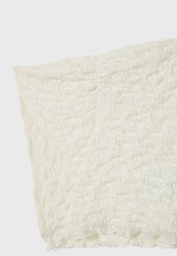 Teksturirani off-white materijal s naboranom površinom, koji ima mekan i lagan izgled te valoviti rub.