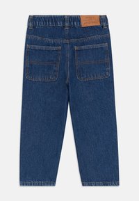 Pantalones de mezclilla azul con cintura elástica, dos bolsillos traseros y costuras en contraste. La tela tiene una textura desgastada y un diseño de pierna recta.