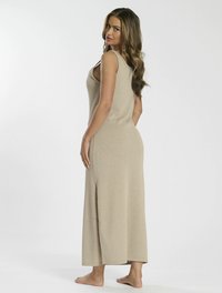 Abito maxi beige senza maniche con una spacco laterale, realizzato in un tessuto testurizzato. Presenta una vestibilità comoda e un scollo modesto.