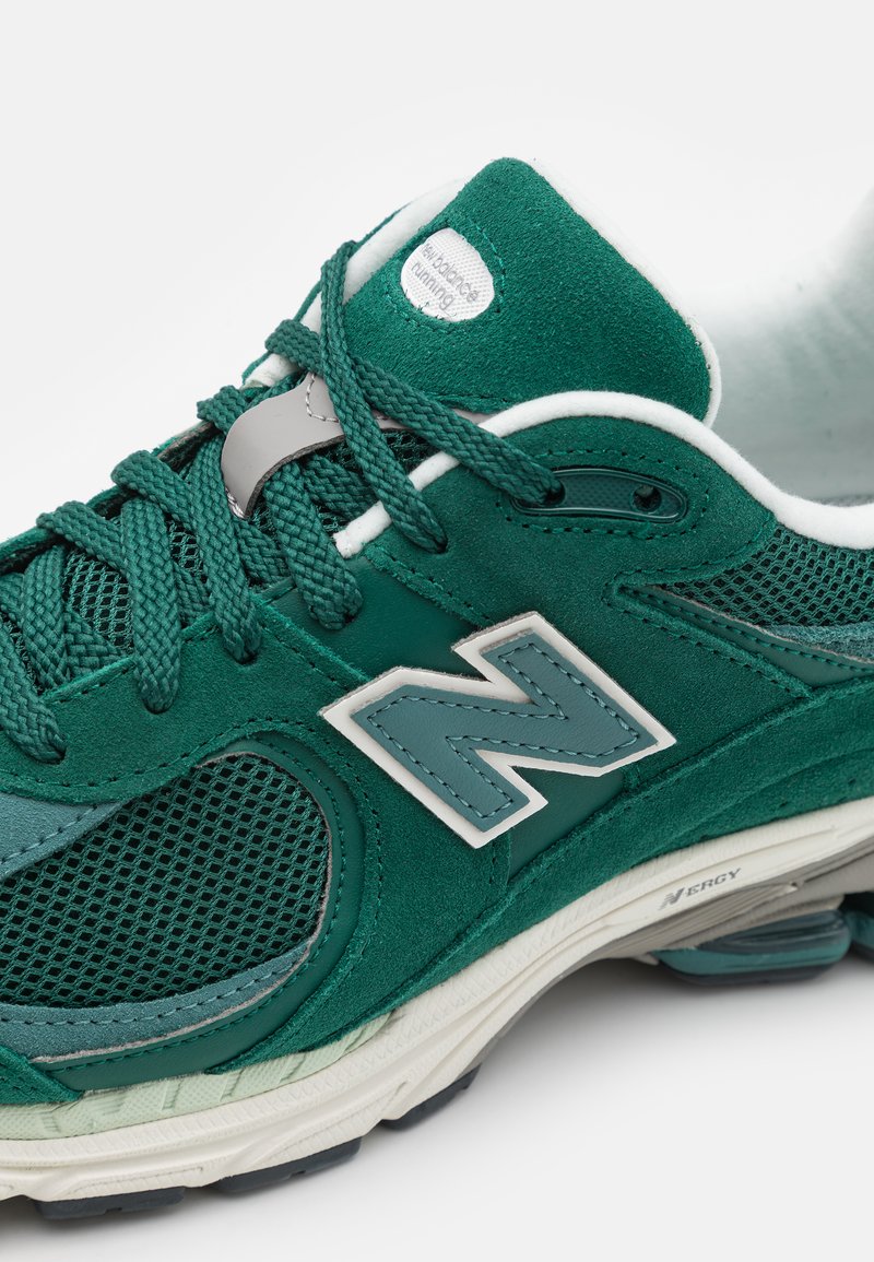 Sneaker verde in suede e rete con lacci texturizzati, un logo bianco di accento e una suola imbottita con componenti grigi e menta.