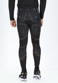 Schwarze Sportleggings mit geometrischen grauen und goldenen Mustern. Der hochgeschnittene Schnitt und die enganliegende Passform fördern die Bewegung. Glattes, dehnbares Material.
