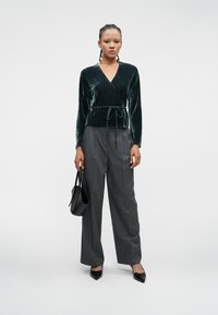 Samettiyöpaita tumman vihreänä pitkähihaisena, vyötärönauha. Yhdistetty korkeavyötäröisten harmaiden housujen ja mustien kärkitossujen kanssa.