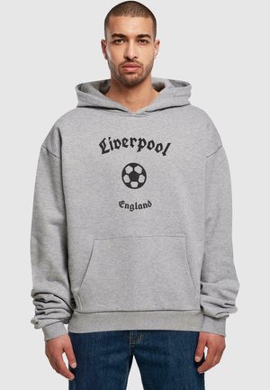 Grå hettegenser med lomme foran, med svart tekst som sier "Liverpool" og et fotballgrafikk. Uformell design, myk stoff.