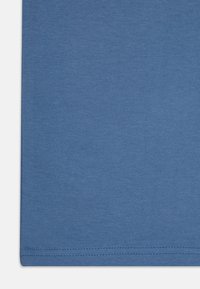 Blå bomullsstoff med en jevn tekstur. Har en rett kant og synlige sømmer langs kantene. Ingen mønstre eller design.