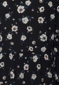 Tecido preto com um padrão floral, apresentando rosas brancas e rosa clara, realçadas por folhas verdes. Inclui uma camada franzida na barra.