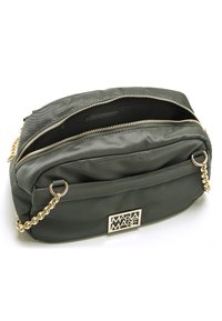 Sac en nylon vert olive avec une anse en chaîne dorée, des compartiments zippés et une plaque logo extérieure. Texture lisse et forme rectangulaire.