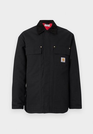 Veste de travail noire en tissu résistant, dotée de deux poches poitrine, d'accents métalliques dorés et d'une doublure intérieure rouge contrastante.