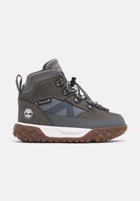 Botte de randonnée imperméable grise et marron avec semelle robuste, laçage à l'avant avec un système à bascule, col rembourré et logo Timberland au talon et sur le côté.