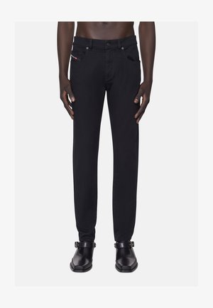 Musta farkut slim fit -mallilla, joissa on etutaskut, pieni logo vyötärön lähellä ja vahvistetut saumat. Yhdistetty mustiin kenkiin.