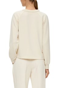 Crème ronde hals sweatshirt met raglanmouwen, zachte textuur, ribgebreide manchetten en zoom, gecombineerd met bijpassende ribgebreide crèmepantalons.