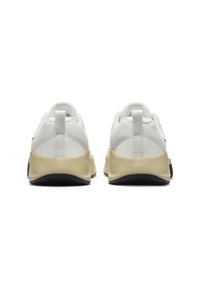 White athletic shoes with a mesh upper, padded collar, and a thick beige midsole. Black outsole with a textured pattern.
