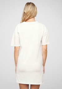 Biała bawełniana sukienka w oversize'owym kroju, z okrągłym dekoltem, krótkimi rękawami i prostym wykończeniem, minimalna tekstura i czysty design.
