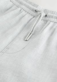 Gray sweatpants featuring a drawstring waist, soft texture, and a subtle weave pattern. Includes a pocket detail on the front.