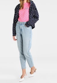 Laivastonsininen pilkullinen takki, vaaleanpunainen pilkullinen paita, vaaleansiniset farkut ja valkoiset slingback-kengät. Rento asu, jossa on kontrastisia kuvioita ja värejä.