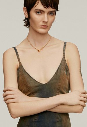 Vestido de mezclilla con escote en V profundo, degradado de azul oscuro a verde, y detalles de costura en naranja; combinado con un collar de múltiples hilos en dorado.
