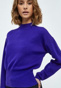 Maglione knit viola con un collo alto, vestibilità rilassata e orlo a costine. Presenta maniche lunghe e tessuto testurizzato.