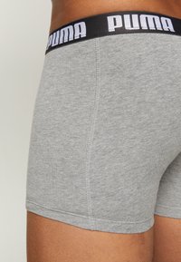 Graue Baumwoll-Boxershorts mit einem schwarzen elastischen Bund und weißem "PUMA"-Branding. Glatte Textur und enganliegendes Design mit feiner Naht.
