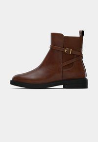 Rudos odinės kulkšnės botai su šonine juosta ir auksiniu sagtimi, juodu guminiu padu ir lygia tekstūra. Klasikinis dizainas su minimaliais akcentais.