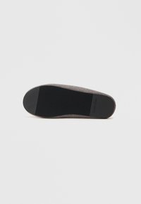 Talpa gri Calvin Klein, cu un fund texturat din cauciuc negru, dotat cu caneluri orizontale și verticale pentru tracțiune și stabilitate.
