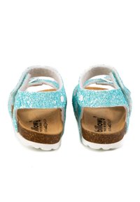 Sandales turquoises scintillantes avec talon ouvert. Doublure intérieure douce, semelle en liège et semelle en caoutchouc blanc. Deux sangles ajustables avec fermetures à pression.