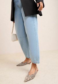 Blugi de un albastru deschis, cu un croi lejer, asortați cu pantofi slingback bej, cu vârf ascuțit, care au un model cu imprimeu de leopard negru. Geantă mică din lanț.