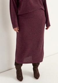 Bordeaux geribbelde gebreide two-piece outfit met een lange trui en rok, met een relaxte pasvorm en een zijsplit, gecombineerd met bruine boven de knie laarzen.