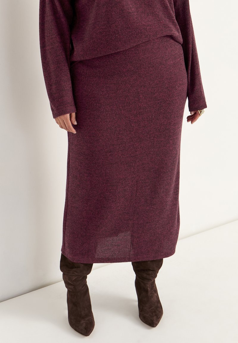 Bordeaux geribbelde gebreide two-piece outfit met een lange trui en rok, met een relaxte pasvorm en een zijsplit, gecombineerd met bruine boven de knie laarzen.