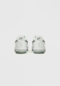 Valged Nike Air tossud, millel on sile nahk ülemine osa, kontrastsed mustad aktsendid ja läbipaistev tald koos selge pehmendusega.