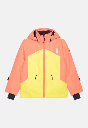 Veste d'hiver à capuche bicolore orange et jaune avec fermeture éclair à l'avant, poches zippées et poignets intérieurs noirs sur fond blanc.