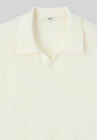 Polo en tricot de couleur écrue avec un motif texturé, comportant un décolleté en V et un col uni. Étiquette indiquant "B2B," taille L.