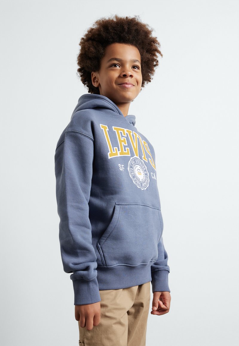 Felpa con cappuccio in misto cotone blu con tasca a marsupio, con logo "LEVIS" in giallo e un emblema grafico sul petto.