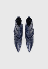 Cizme de gleznă din piele bleu marin, cu un design drapat, vârf ascuțit și o bucată scurtă de prindere în partea de sus. Textură netedă, fără elemente metalice vizibile.