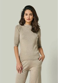 Hellbeige geripptes Sweatshirt mit hohem Kragen, 3/4-Ärmeln und dezenten Puffdetails an den Schultern. Weicher Stoff, enganliegende Passform.