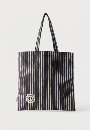Crno-bijela torba za nošenje s okomitim prugama, dvije ručke i malom oznakom s riječju "marimekko" blizu donjeg lijevog kuta.