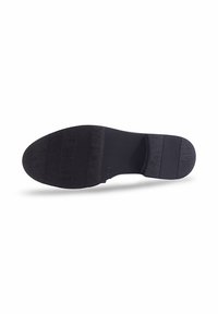 La semelle noire de la chaussure présente une surface plate et texturée avec des rainures horizontales et un bout arrondi. Le matériau semble caoutchouteux avec une finition mate.