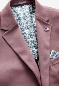 Fialový texturovaný blazer s geometrickým modro-bílým vzorem na podšívce a kapesníčkem, s malým kovovým akcentem a detailním prošíváním.