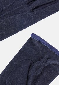 Tamsiai mėlynos vilnonės pirštinės su minkšta tekstūra. Ypatybės: prigludę kraštai ir sklandus, kontrastingos medžiagos apdaila rieše.