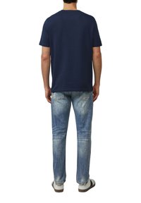 Marineblauwe katoenen t-shirt met een klassieke ronde hals, gecombineerd met lichtgewassen denim jeans met een rechte pijp en minimale vervaging.