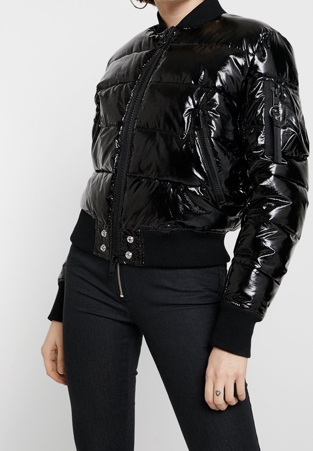 Svart, glansig puffjacka med en figurnära design, ribbade ärmslut och fåll, dragkedjefickor och central dragkedjestängning.
